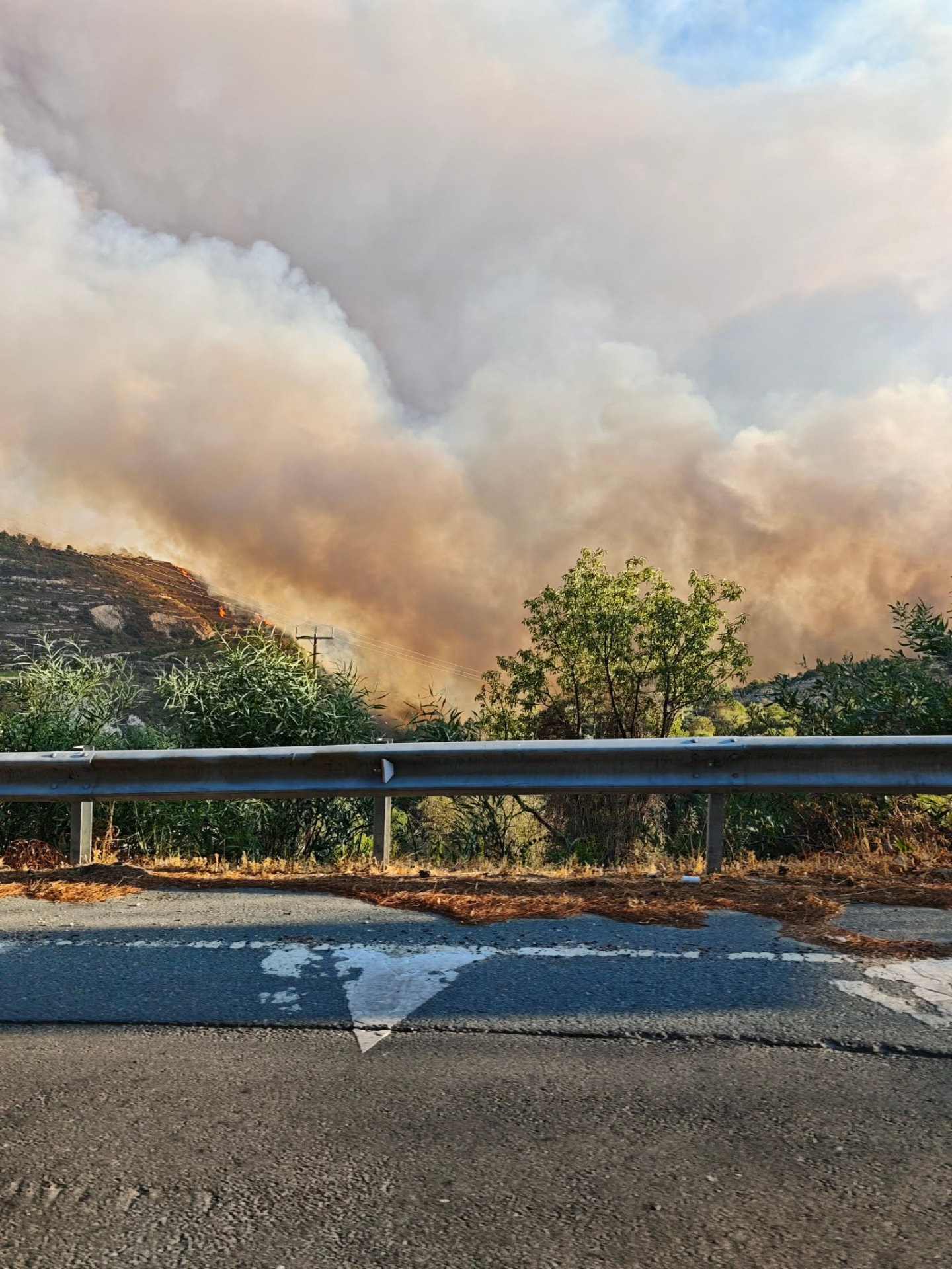 Πλαγιά που καίγεται δίπλα στον δρόμο, από το στηθαίο